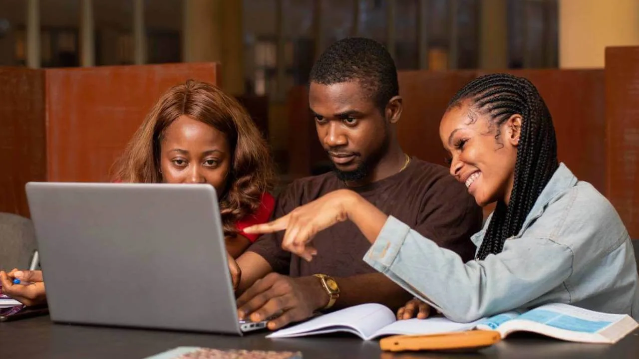 Three TecPal learners working through a build together on a laptop.